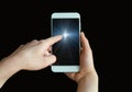 The woman`s index finger points to the blue screen of a smartphone, a mobile phone on a black background. Point your finger at the