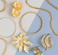 Woman`s Jewelry. Vintage jewelry background. Beautiful gold tone brooches, braceletes, necklaces and earrings on blue background.