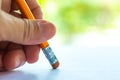 Woman left Hand hold orange triangular pencil, Rubber to delete from white paper, Bokeh green garden background, Notebook, Close