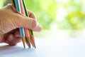 Woman left Hand holding 5 multicoloured pencils Yellow, Green, Pink, White, Blue colour, writing letter on white paper Royalty Free Stock Photo