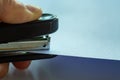 Woman left hand holding stapler and stapling white paper on grey colour background, Close up & Macro shot, Selective focus Royalty Free Stock Photo