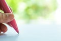 Woman left Hand holding a pink pen, writing letter on white paper, Bokeh green garden background, Notebook, Communication Royalty Free Stock Photo