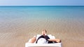 Woman`s leg lay on the white armchair on the beach