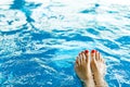 Woman`s leg with red pedicure in pool - toes