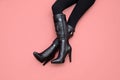 Woman`s legs in black leather knee high stiletto high heels boots isolated on pink background. Leg to leg, flatlay, top front vie