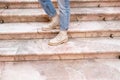 Woman`s legs in blue twisted jeans and in beige boots on pink marble staircase. Front view, copy space