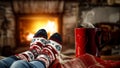 Woman`s legs with christmas socks and a red mug of coffee or tea and home interior with fireplace and dark wall background. Royalty Free Stock Photo