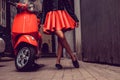 Woman`s legs near red motor scooter. Royalty Free Stock Photo