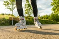 Woman`s legs with roller blades at sunny day. Close-up shot of white Inline skates on the path. Royalty Free Stock Photo