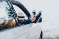 Woman`s legs in sneakers in the window car with straw hat. Girl in jeans in the car with her legs crossed. Royalty Free Stock Photo