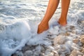Woman's legs on the stone beach with water Royalty Free Stock Photo