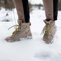 Woman`s legs in stylish pants in winter brown leather fashion boots on snow. Close-up