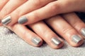 Woman`s nails with shiny silver hybrid manicure