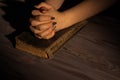 Woman`s praying to God with folded hands on an old vintage holy bible.