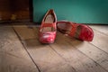 Woman`s red high heel dress shoes lying on rustic wooden floor