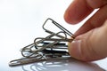 Woman right hand pick up Paper clip on white acrylic background, Close up & Macro shot, Selective focus, Business, Education Royalty Free Stock Photo