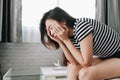 Woman sad depressed sitting on a sofa in the living room