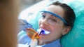 Woman in safety glasses undergoing treatment at dentist using light lamp Royalty Free Stock Photo