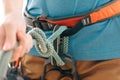 Woman in safety harness holding mountaineering rope knot eight, close-up.