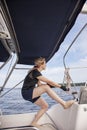 Woman sailing pulling ropes to adjust sails on sailboat