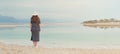 Woman in sailor striped dress near seaside of Dead Sea beach. Travel, summer vacation, holiday, freedom concept. Digital detox. Royalty Free Stock Photo