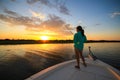 Woman Saltwater Fishing Casting From Boat During Sunrise