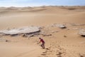 Woman sand boarding on Sahara Desert down the dune, Africa