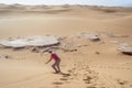 Woman sand boarding on Sahara Desert down the dune, Africa