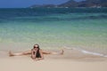 woman on the sand by the sea sits on a twine and laughs