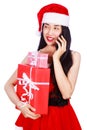 Woman in Santa Claus clothes calling on mobile phone with gift b Royalty Free Stock Photo