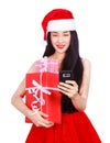 Woman in Santa Claus clothes looking at mobile phone with gift b Royalty Free Stock Photo