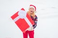 Woman in Santa Claus dress giving you big red gift over white snow background. Woman present red gift box with ribbon Royalty Free Stock Photo