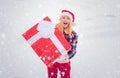 Woman in Santa Claus dress giving you big red gift over white snow background. Woman present red gift box with ribbon Royalty Free Stock Photo