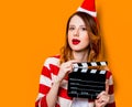 Woman in Santa Claus hat with filmmaking clapperboard