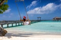 Woman with red santa claus hat sits on a swing on a tropical beach Royalty Free Stock Photo