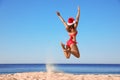 Woman in Santa hat and bikini jumping on beach, space for text. Christmas vacation Royalty Free Stock Photo