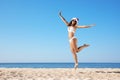 Woman in Santa hat and bikini jumping on beach, space for text. Christmas vacation Royalty Free Stock Photo