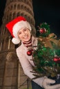 Woman in Santa hat with Christmas tree near Leaning Tower, Pisa Royalty Free Stock Photo