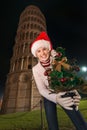 Woman in Santa hat with Christmas tree near Leaning Tower, Pisa Royalty Free Stock Photo