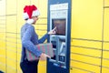 Woman with santa hat client using automated self service post te