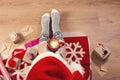 Woman in santa hat drinking cappuccino coffee and sitting on the wooden floor. Close-up of female legs in warm socks with a deer w Royalty Free Stock Photo
