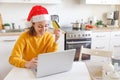 Woman in Santa hat shopping online and paying with gold credit card. Young girl with laptop buying Christmas gift present on Royalty Free Stock Photo