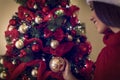 Woman in Santa hats placing a ornament on a Christmas tree