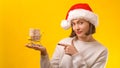Woman Santa helper holding shopping cart. Small cart with money for christmas gifts. Christmas shopping and sales. New Year Royalty Free Stock Photo