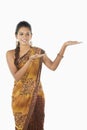 Woman in sari smiling with welcoming hand gesture. Conceptual image