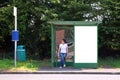 Woman sat at a bus stop next to blank billboard Royalty Free Stock Photo