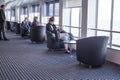 Woman sat in a chair in the public seating area inside a ferry by the window using her mobile phone