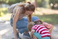 A woman sat down next to her two children in the park and looking down at the ground Royalty Free Stock Photo