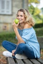 woman sat on outdoor bench eating apple Royalty Free Stock Photo