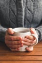 Woman sat at table with mug of tea wearing cozy gray cardigan